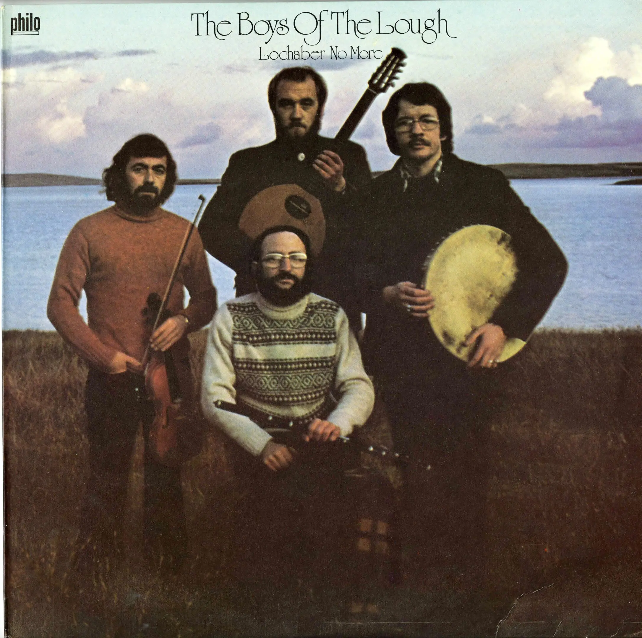 Four men posing with musical instruments outdoors.