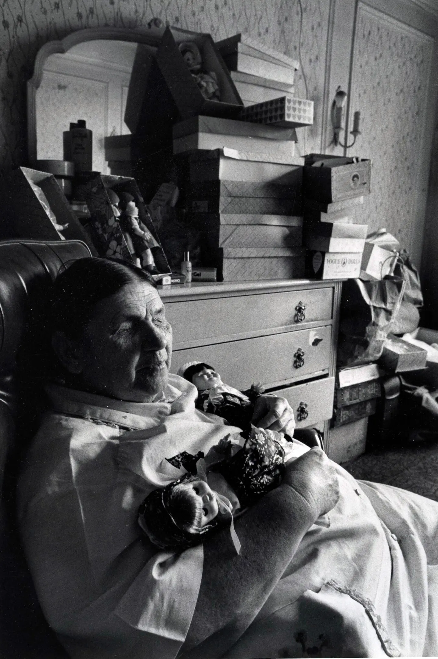 Woman resting in chair holding two dolls.