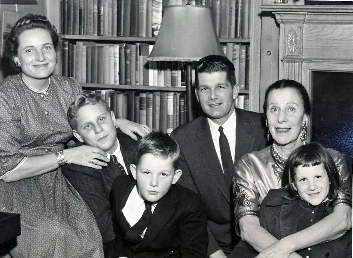 Family posing in front of bookshelves, smiling.