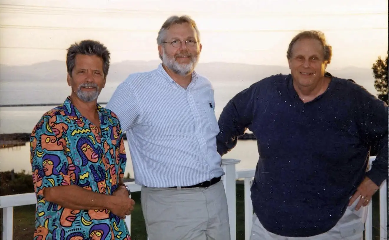 Three men posing by a scenic view.
