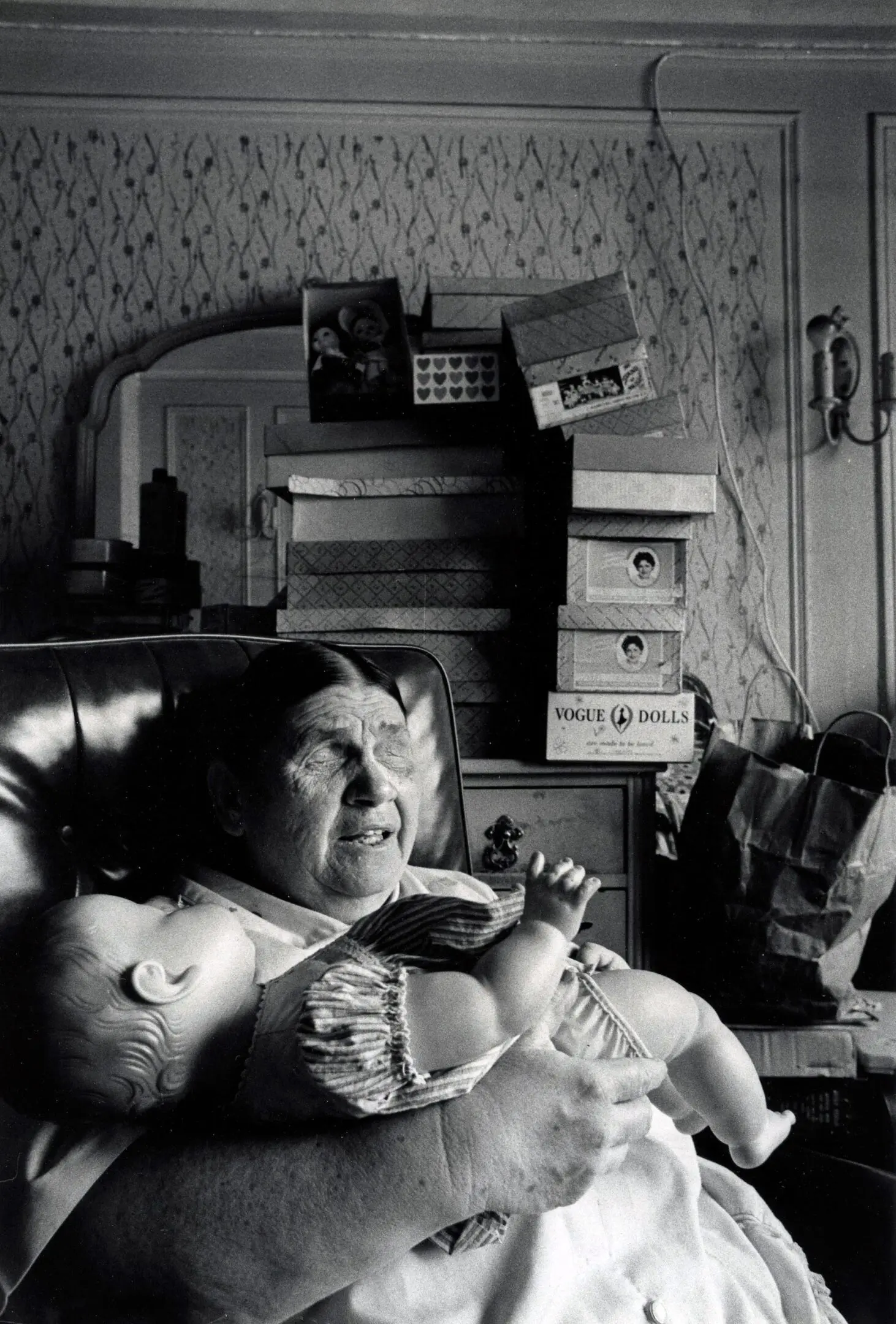 Elderly woman holding a doll, sitting indoors.