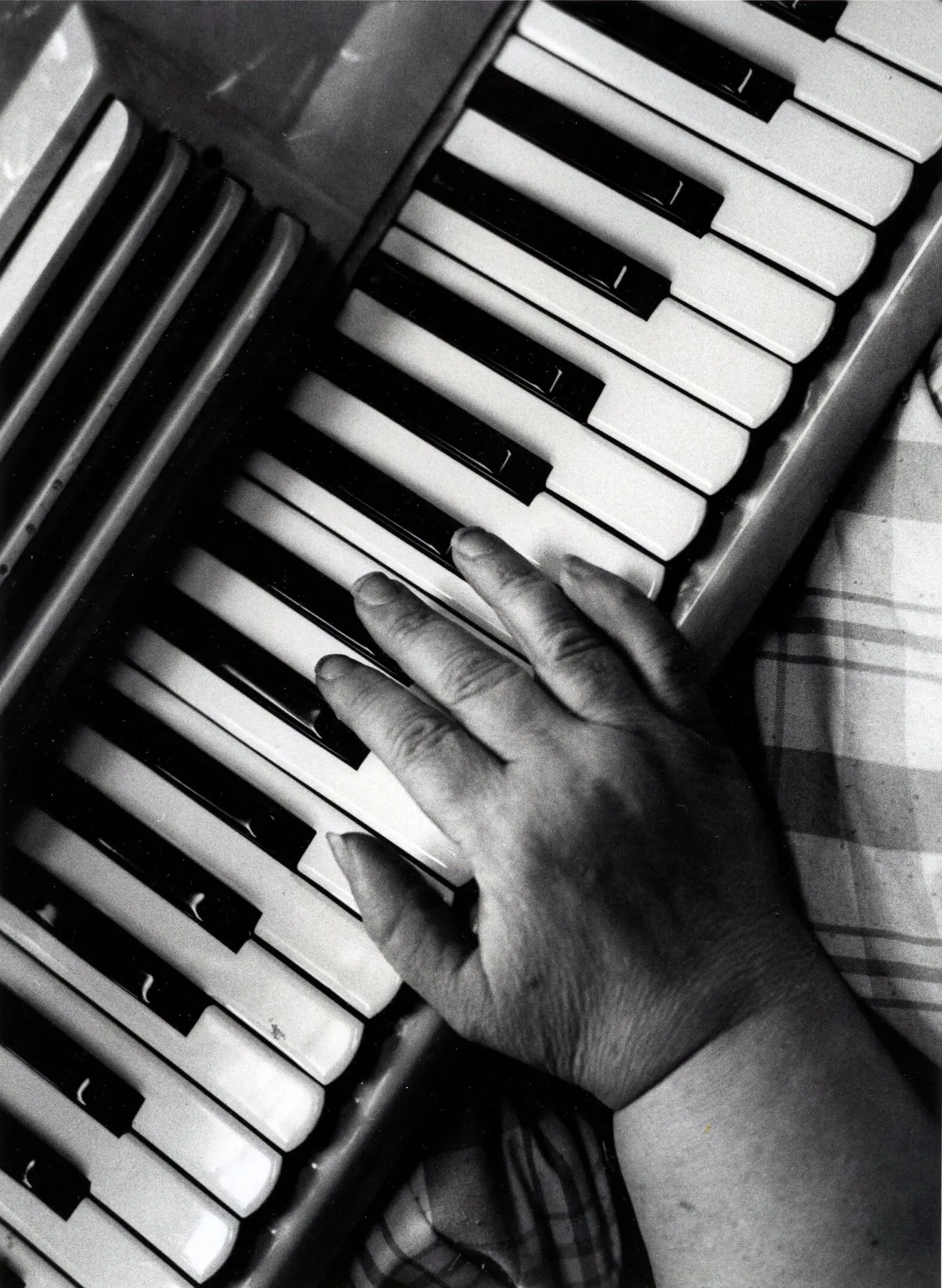 Hand playing a piano keyboard.