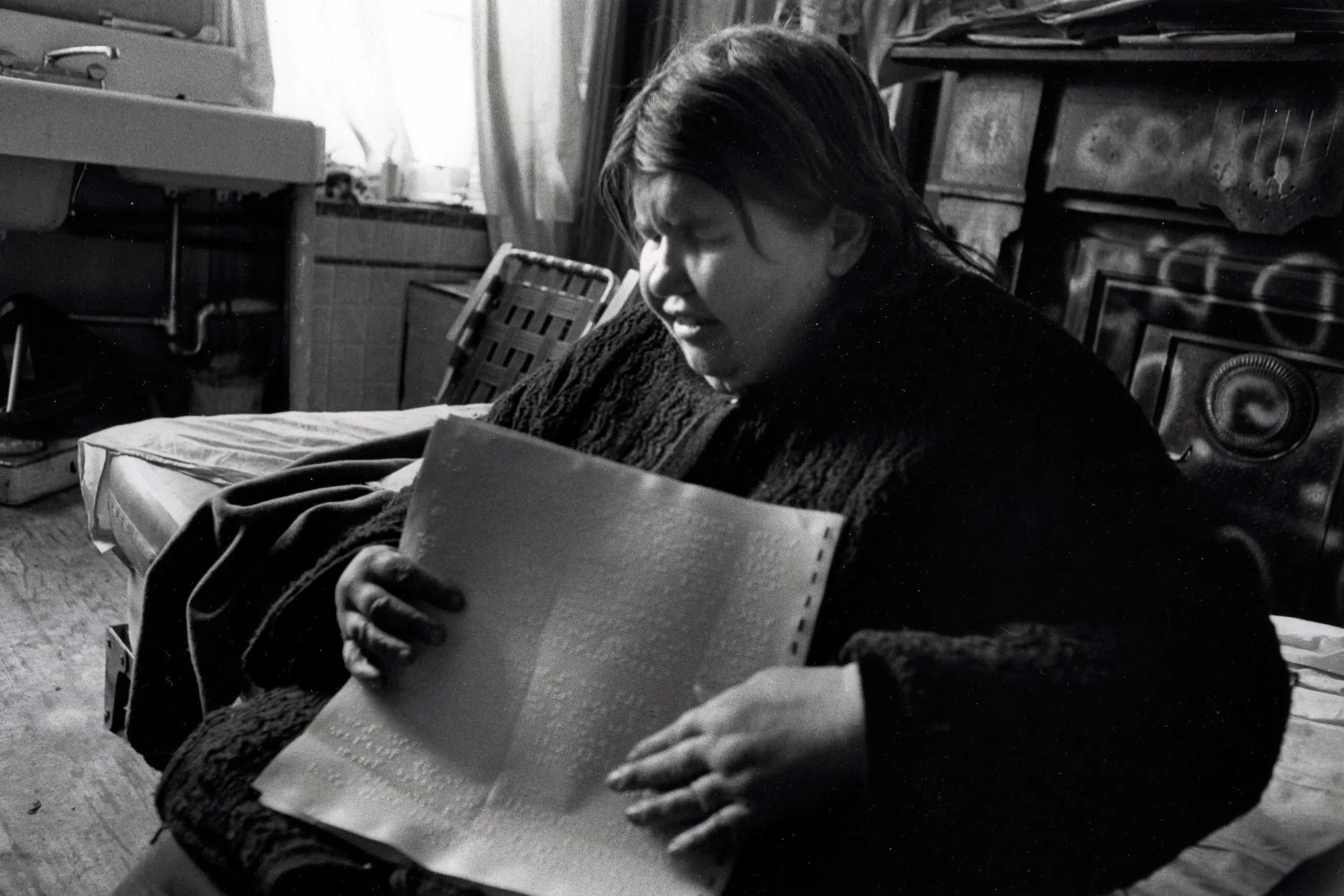 Person reading Braille in dimly lit room.