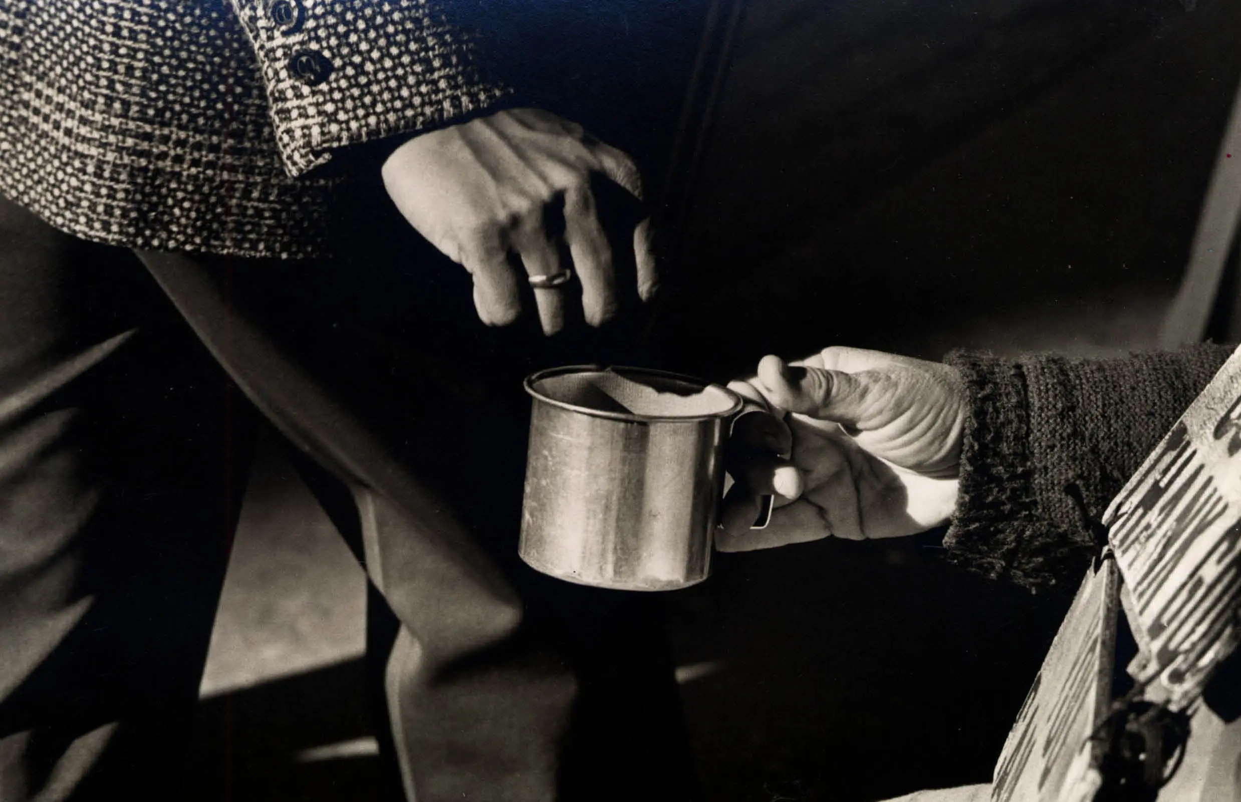 Hands exchanging a metal cup, close-up.
