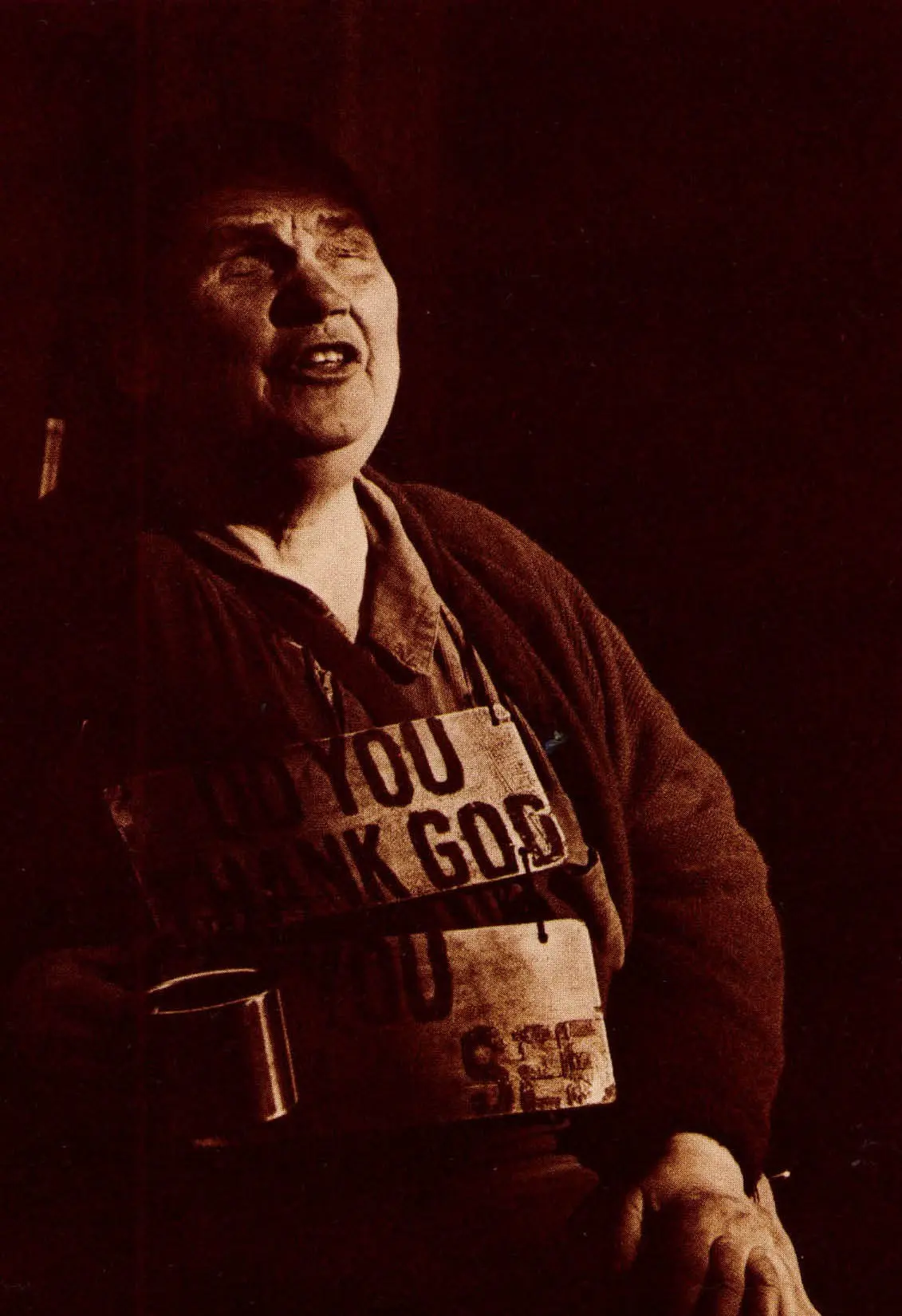 Person holding a cup, wearing a sign.