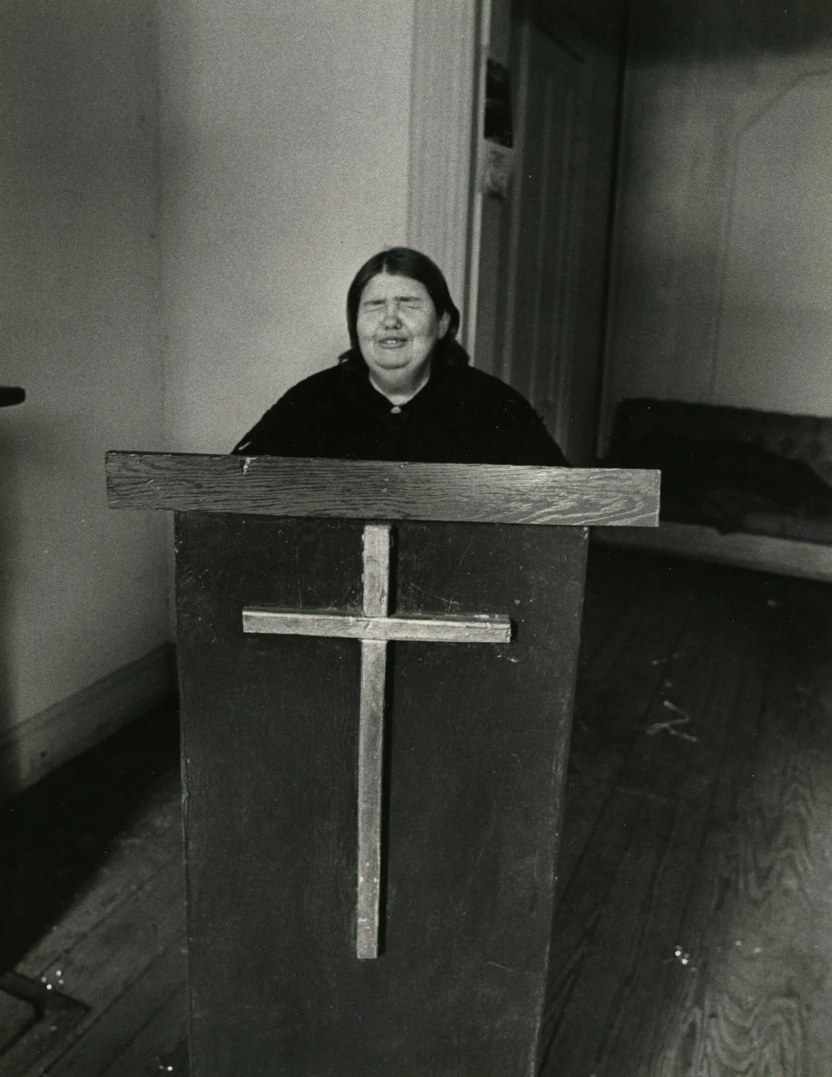 Person speaking at a wooden lectern indoors.