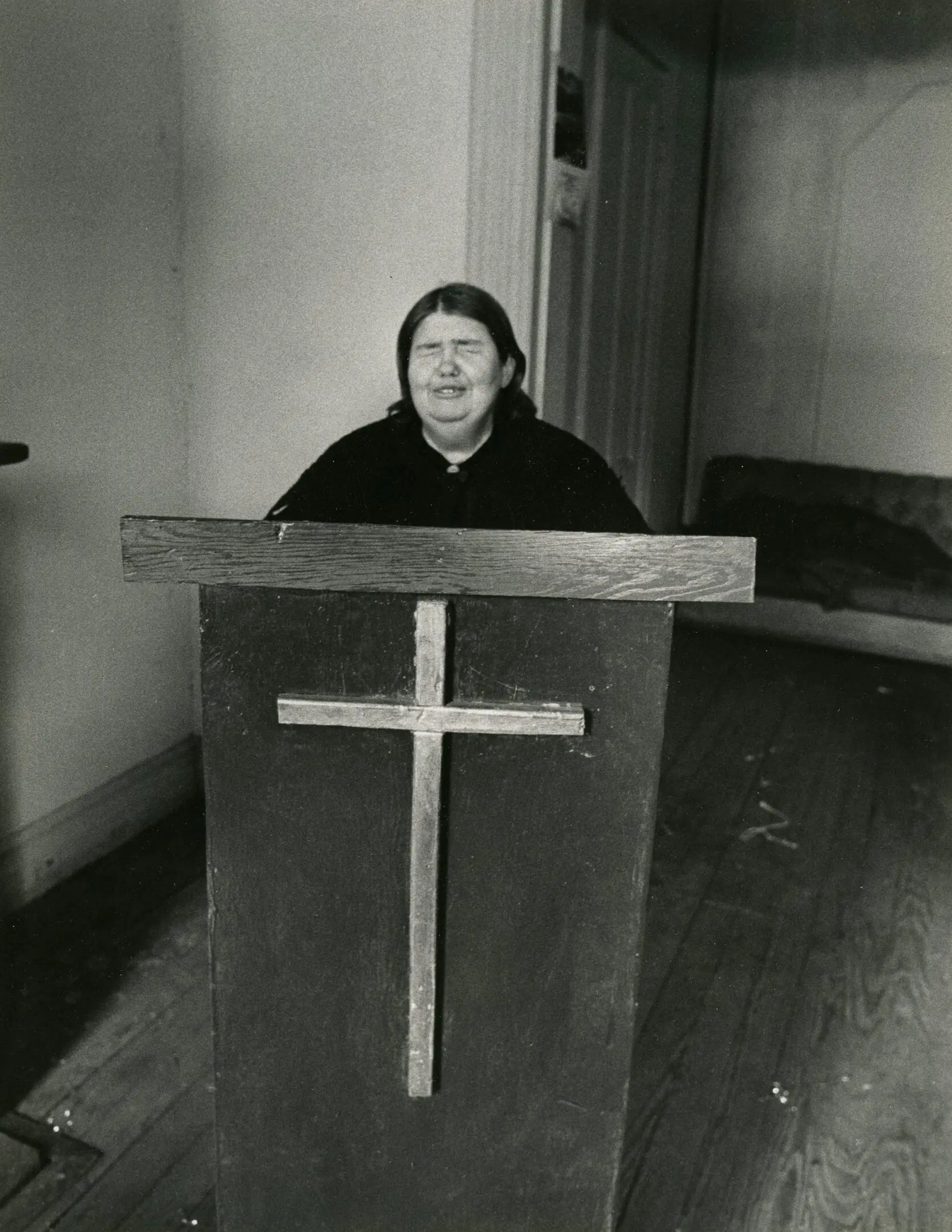 Person standing at pulpit with cross.