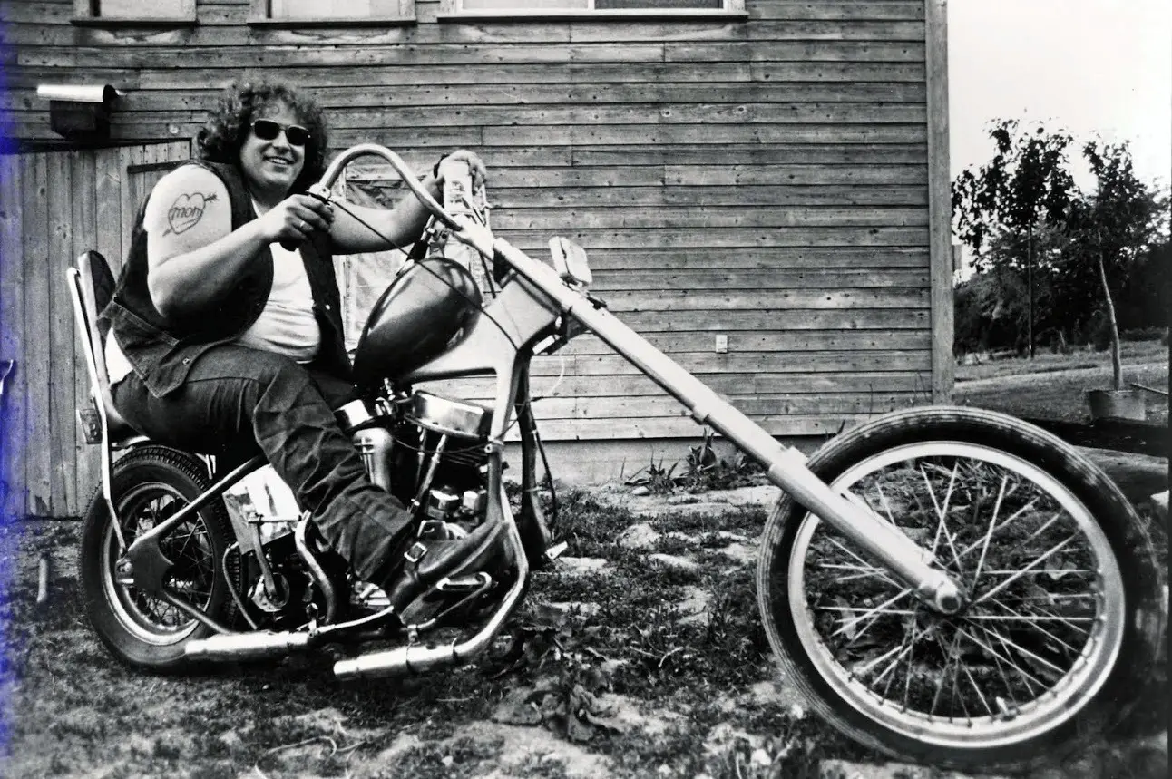 Man sitting on a custom motorcycle, smiling.