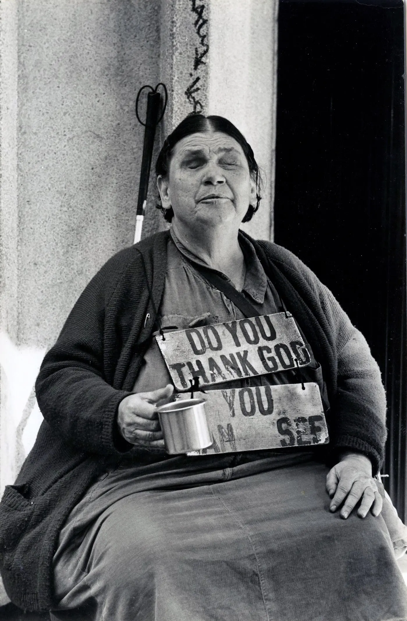 Older woman holding mug, wearing signboard.