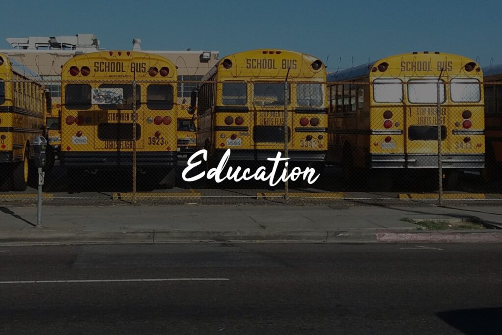 Yellow school buses parked behind fence.