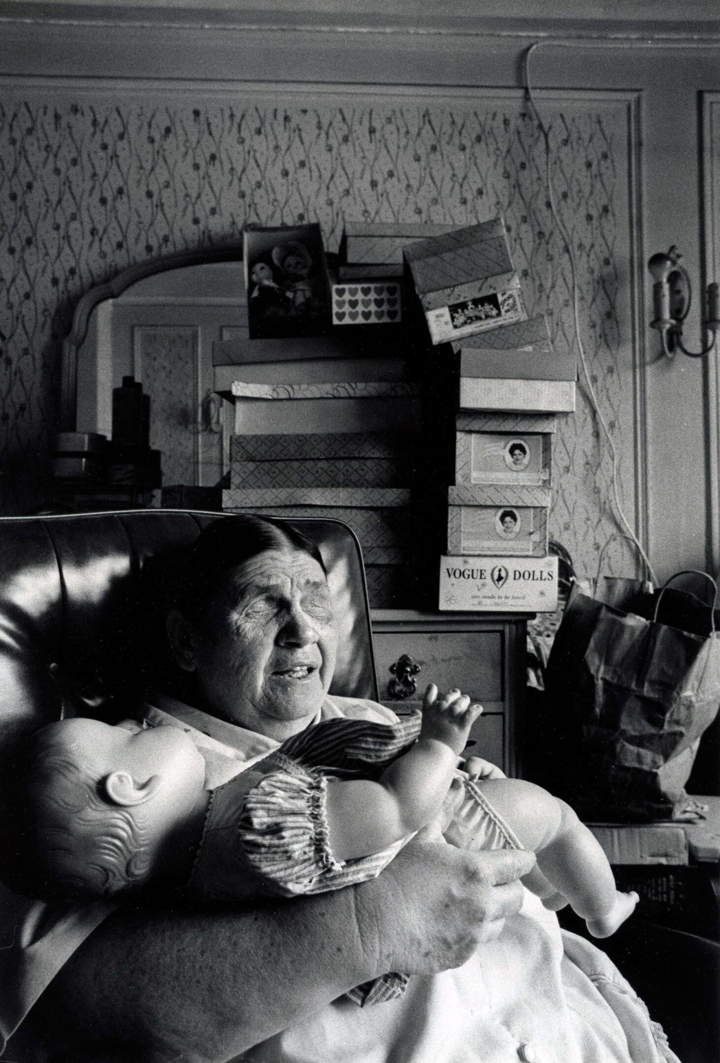 Elderly woman holding a doll, sitting indoors.