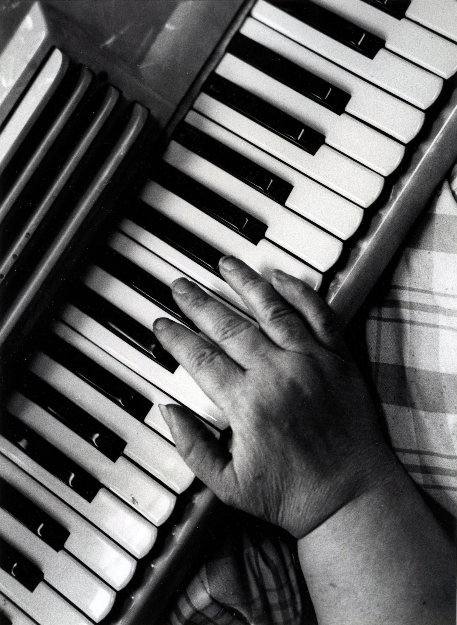 Hand playing a piano keyboard.