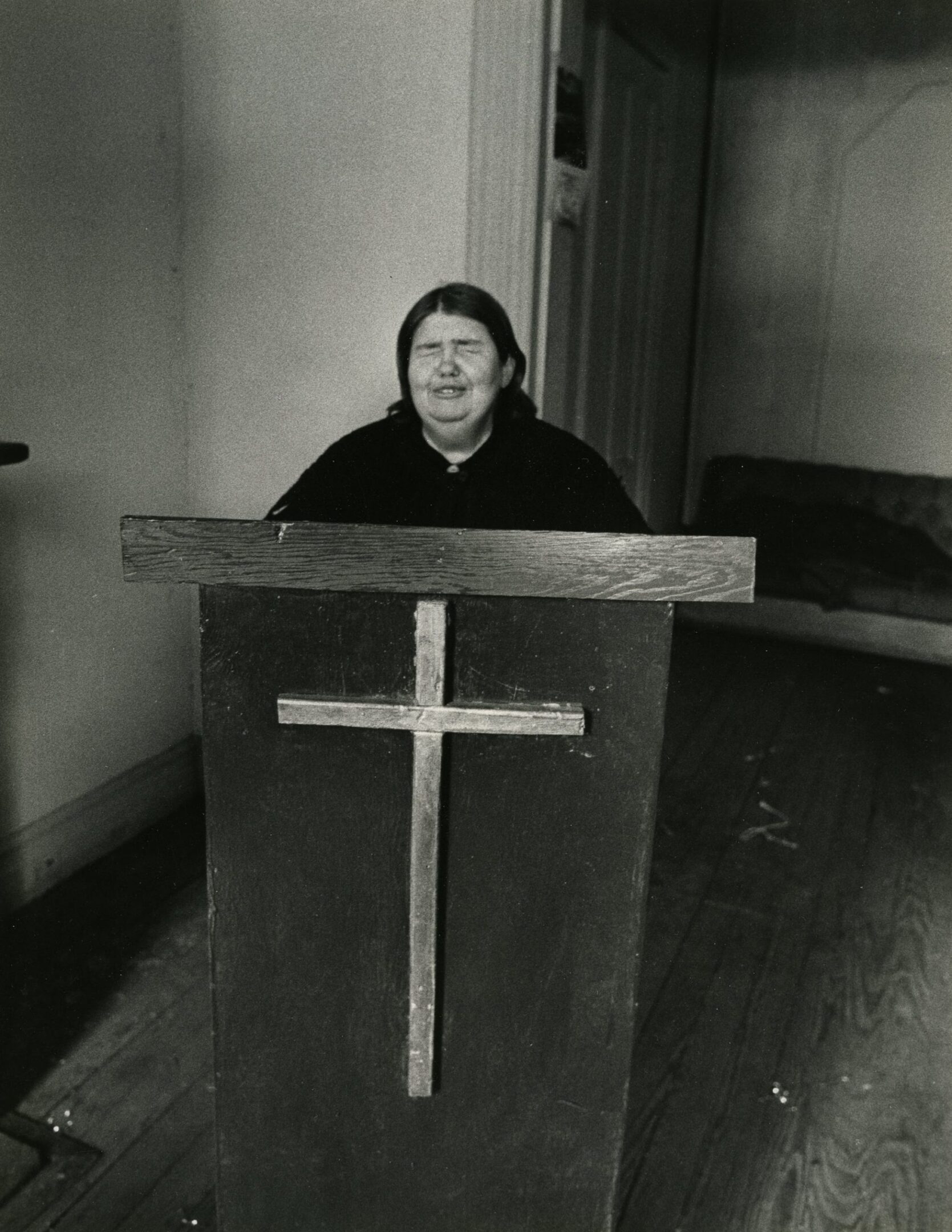 Person speaking at a wooden lectern indoors.