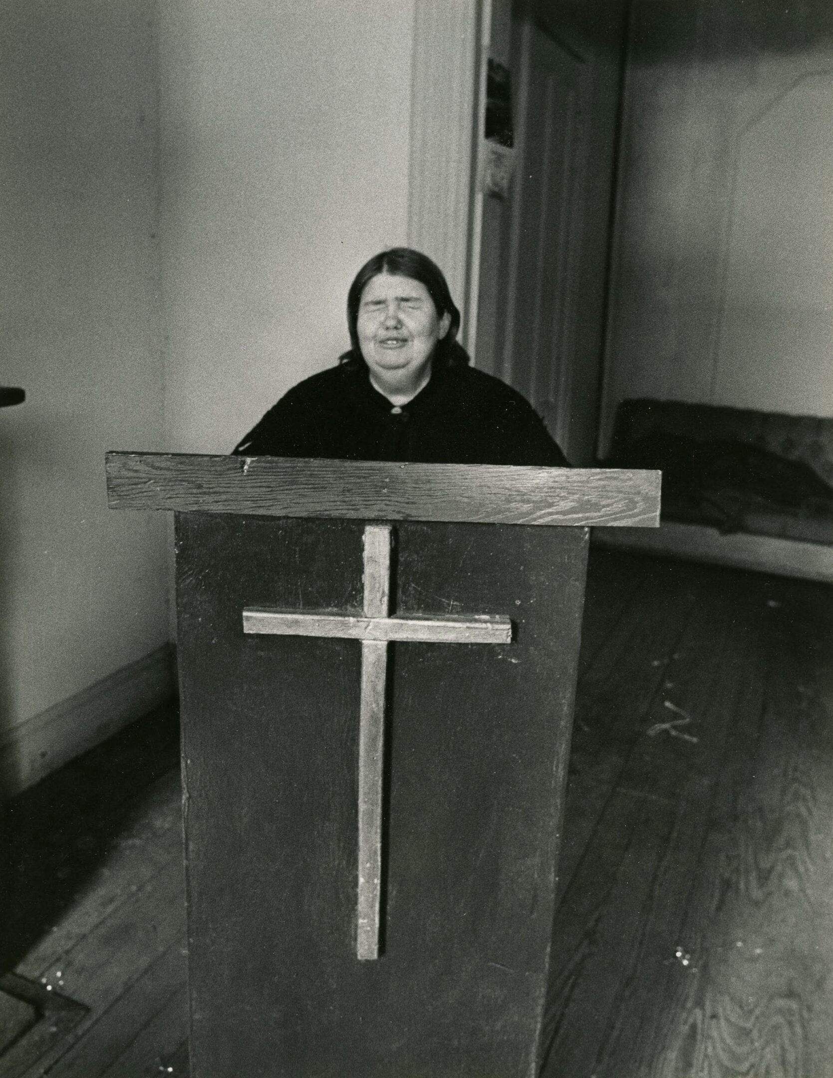 Person standing at pulpit with cross.