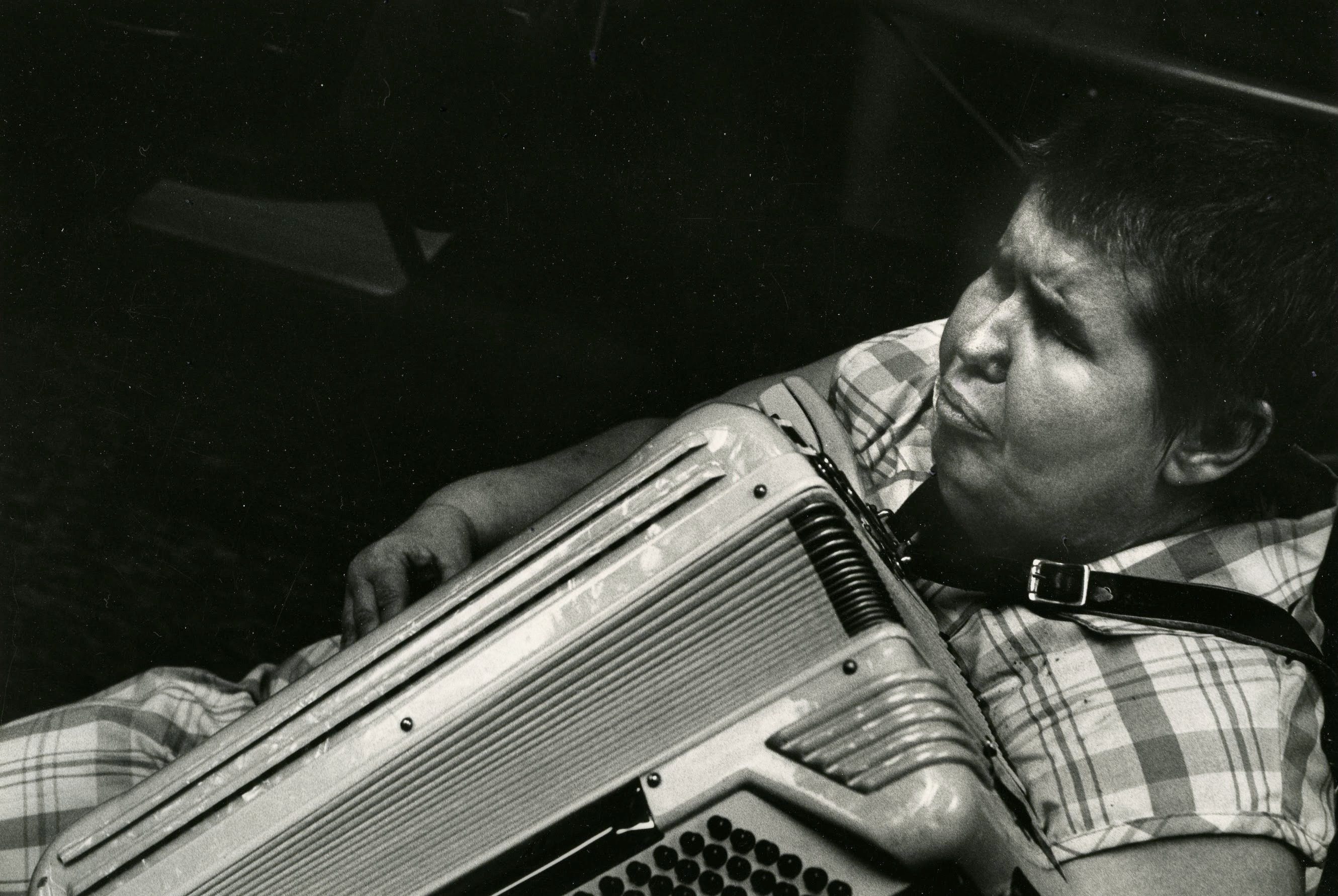 Person playing accordion in black and white.