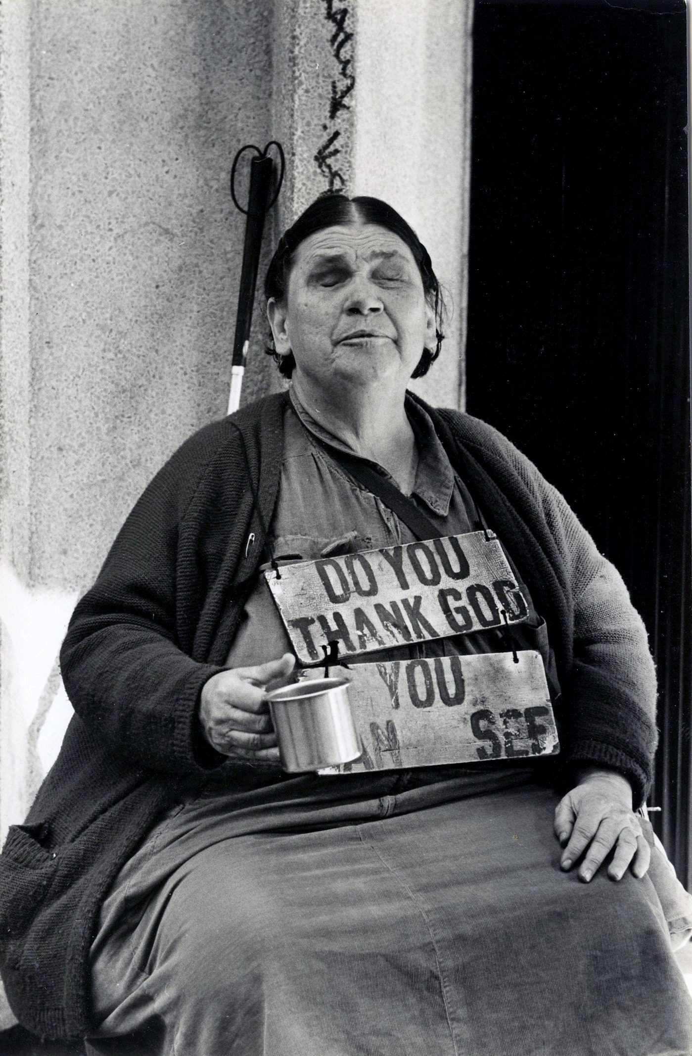 Older woman holding mug, wearing signboard.